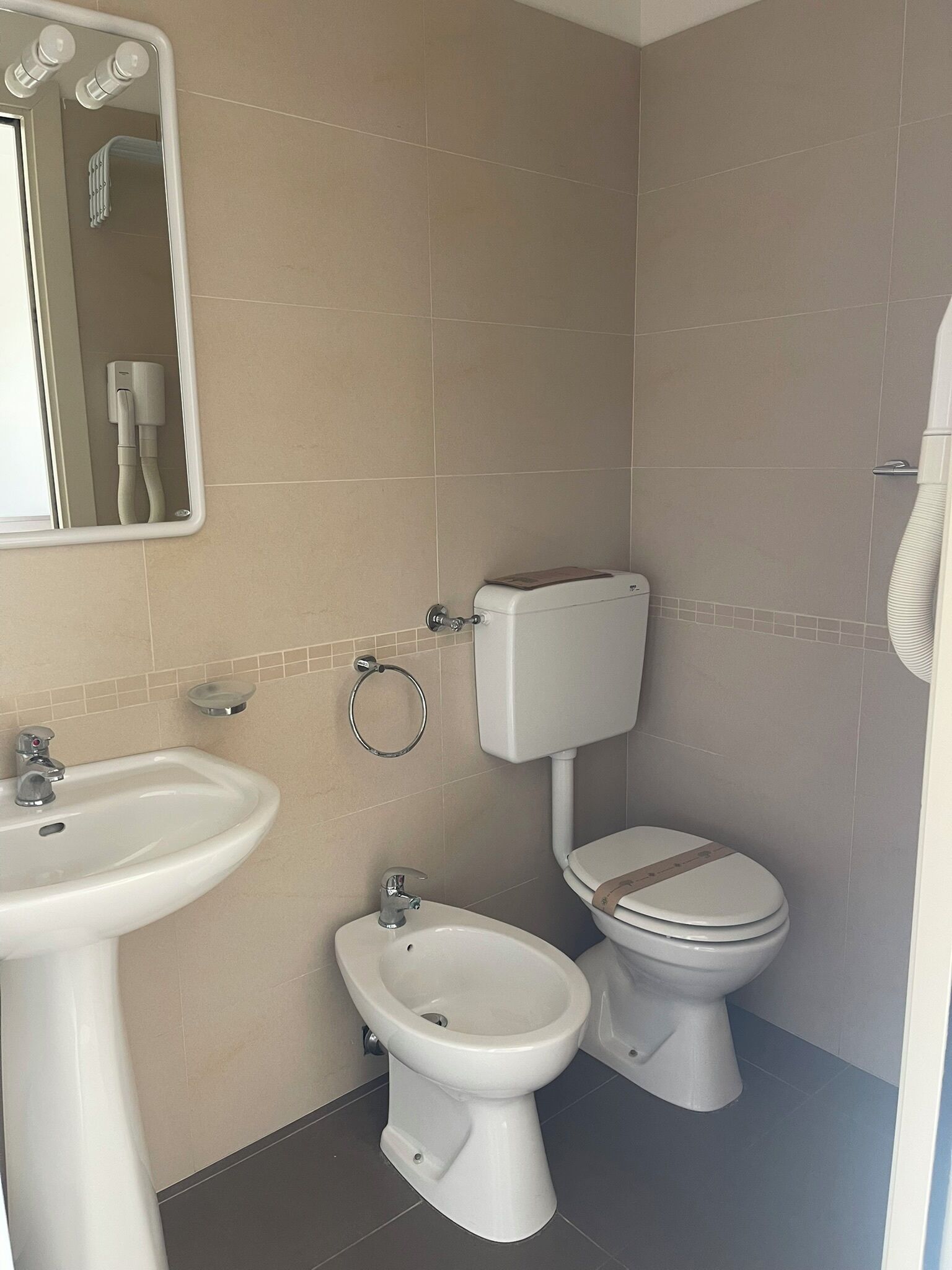 Ein Badezimmer mit Waschbecken, Bidet, Toilette und Spiegel.