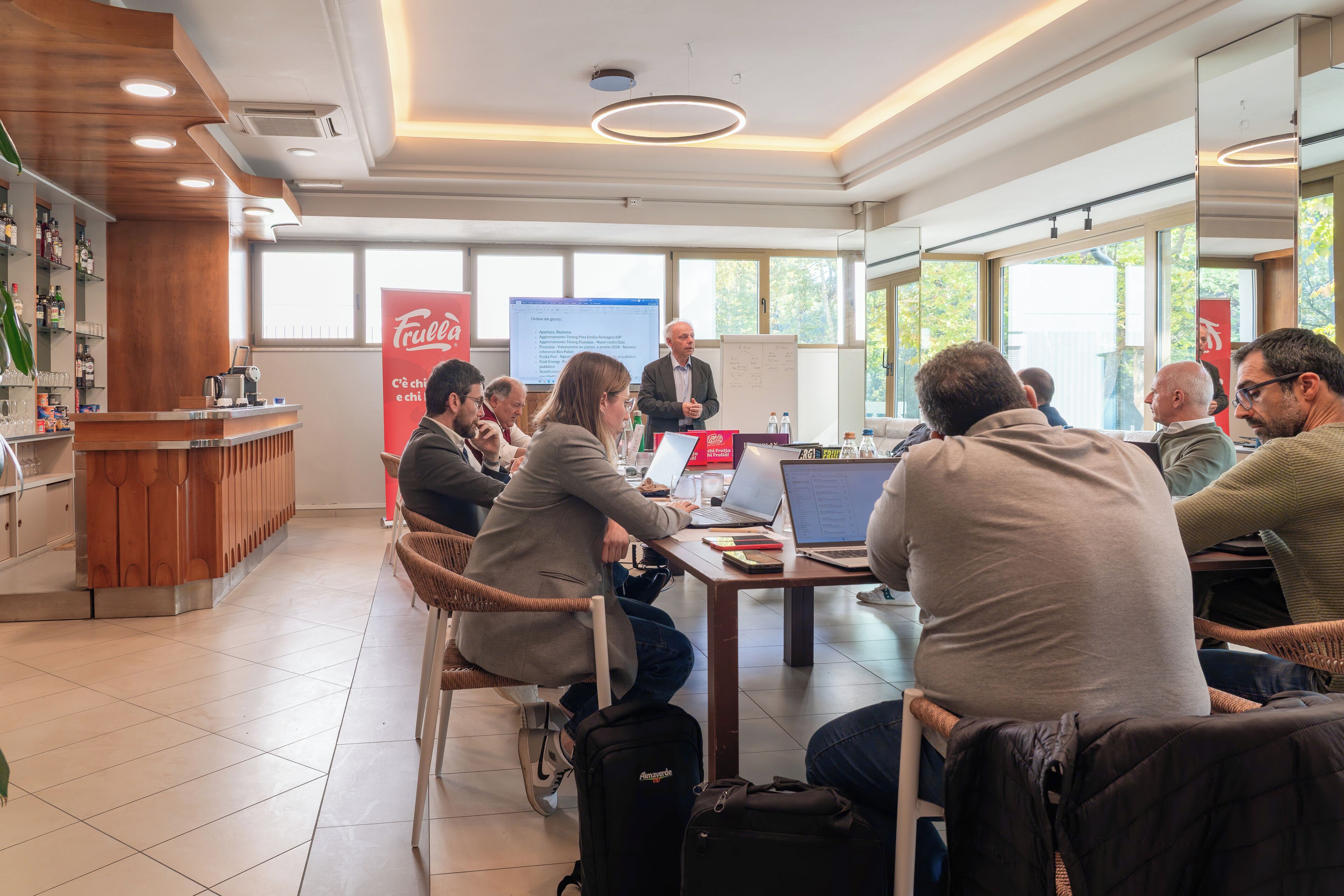 A conference room with a whiteboard, a presentation screen, and a bar area with bottles and glasses.