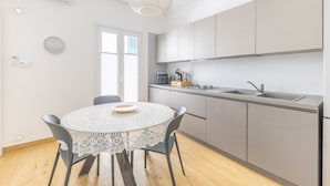 A modern kitchen with a round table, chairs, and a pendant light. - Vico21 Apartment in Central Modica with Balcony, Wi-Fi, and Air Conditioning (Modica)