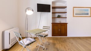 A room with a flat-screen TV, a standing lamp, a drying rack, a wooden cabinet, and a framed picture on the wall. - Vico21 Apartment in Central Modica with Balcony, Wi-Fi, and Air Conditioning (Modica)