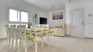 A dining area with a table covered by a polka dot tablecloth, white chairs, and a beige sofa.