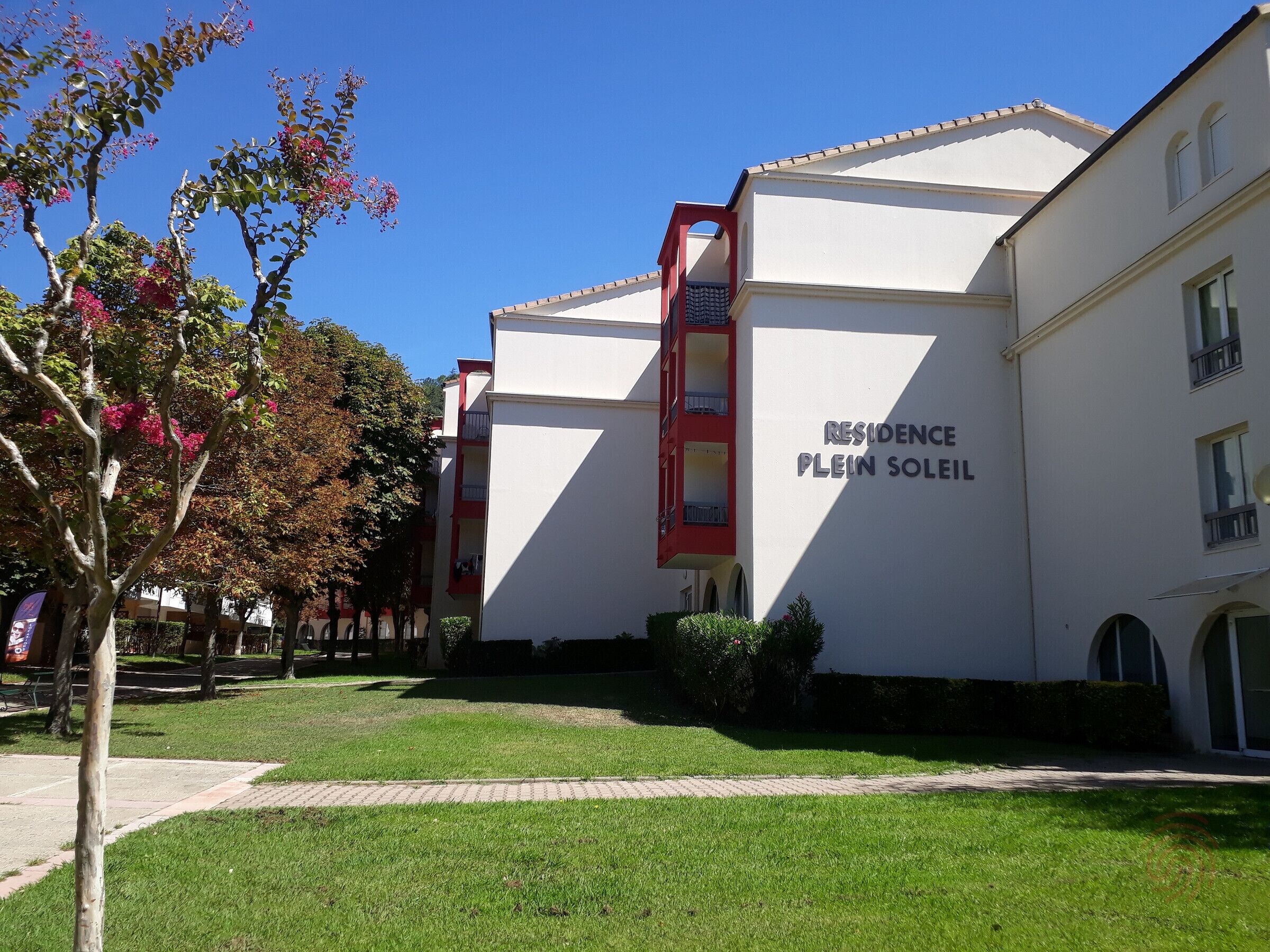 Um edifício com uma placa que diz "RESIDENCE PLEIN SOLEIL", indicando um complexo residencial.