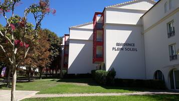 Um edifício com uma placa que diz "RESIDENCE PLEIN SOLEIL", indicando um complexo residencial.