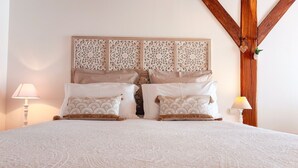 Una cama con colcha estampada, dos almohadas con diseño de abanico y un cabecero decorativo con motivos intrincados.