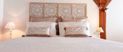 A bed with a patterned bedspread, two pillows with a fan-like design, and a decorative headboard with intricate patterns.