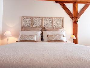 Un lit avec une couvre-lit à motifs, deux oreillers ornés d’un motif en éventail et une tête de lit décorative aux motifs complexes.