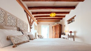 Ein Schlafzimmer mit einem großen Bett, Holzbalken, einer Hängelampe und einem Kleiderschrank.