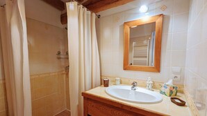 Une salle de bain avec un meuble-lavabo en bois, un évier, un miroir et un espace douche.