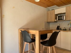Une petite cuisine avec des meubles en bois, un four à micro-ondes et une table avec deux chaises.