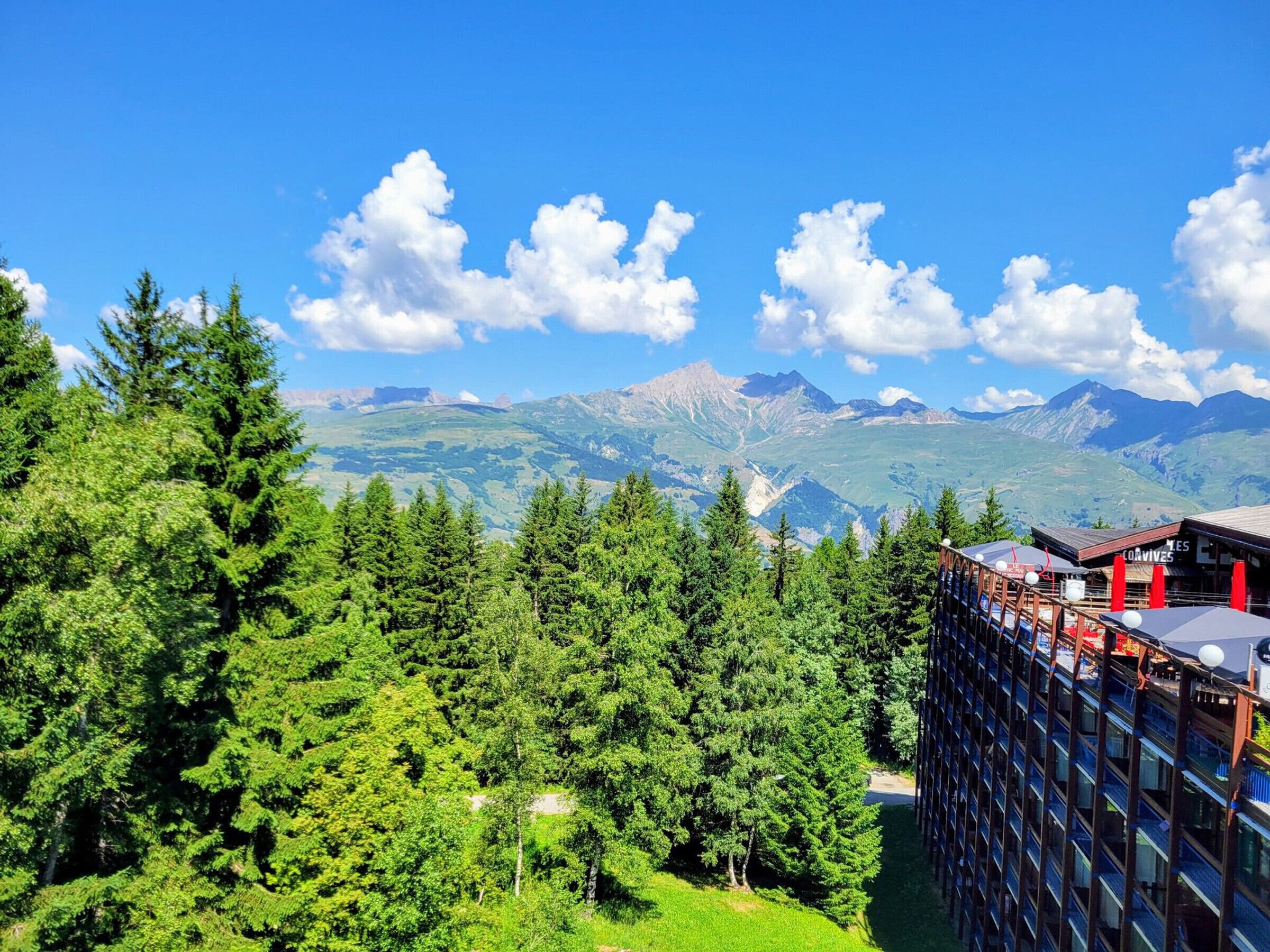 Ein Hotel mit modernem Design, umgeben von dichtem Grünwald und Bergen im Hintergrund.