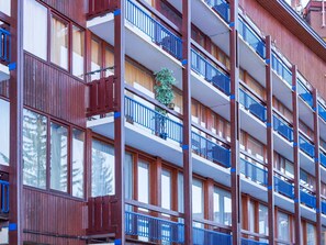 A multi-story building with balconies, wooden exterior, and large windows.