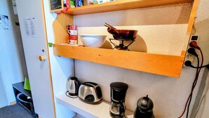 A kitchenette with a coffee maker, toaster, and kettle on the countertop.