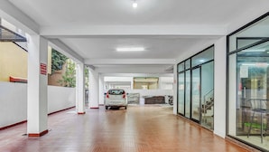 A spacious corridor with a tiled floor, a parked car, and a staircase leading to an upper level. - Season4 Residences 1-BHK furnished appt (Chennai)