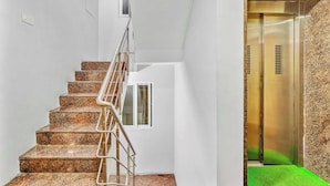 A modern interior with a marble staircase, a small window, and a metallic elevator. - Season4 Residences 1-BHK furnished appt (Chennai)