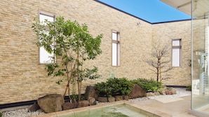 A modern building with a brick exterior, a small outdoor pool, and potted plants.