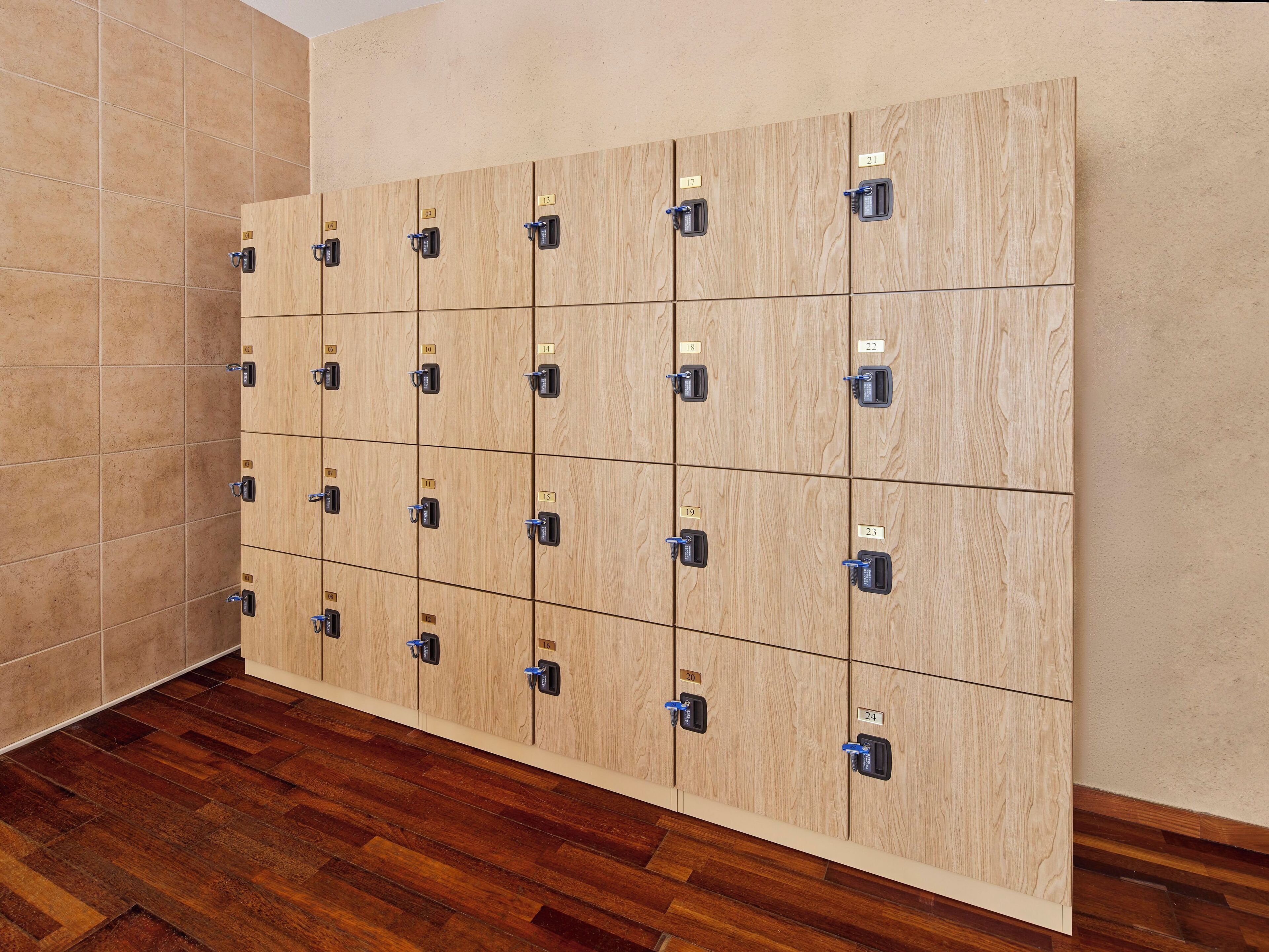 A row of wooden lockers with numbered labels, a tiled wall, and a wooden floor.