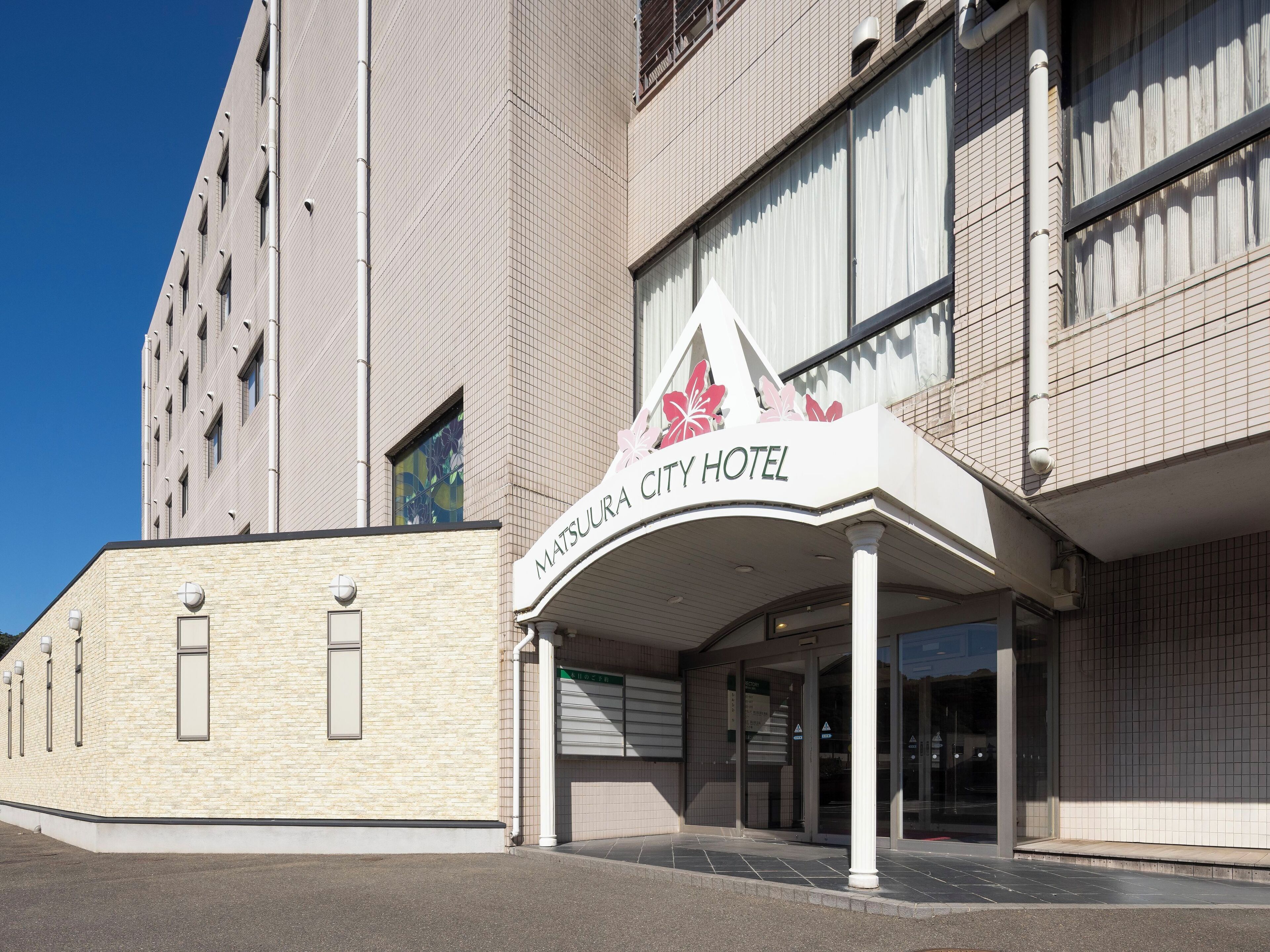 La façade de l’hôtel Matsuu City, avec son entrée imposante et un ciel dégagé.