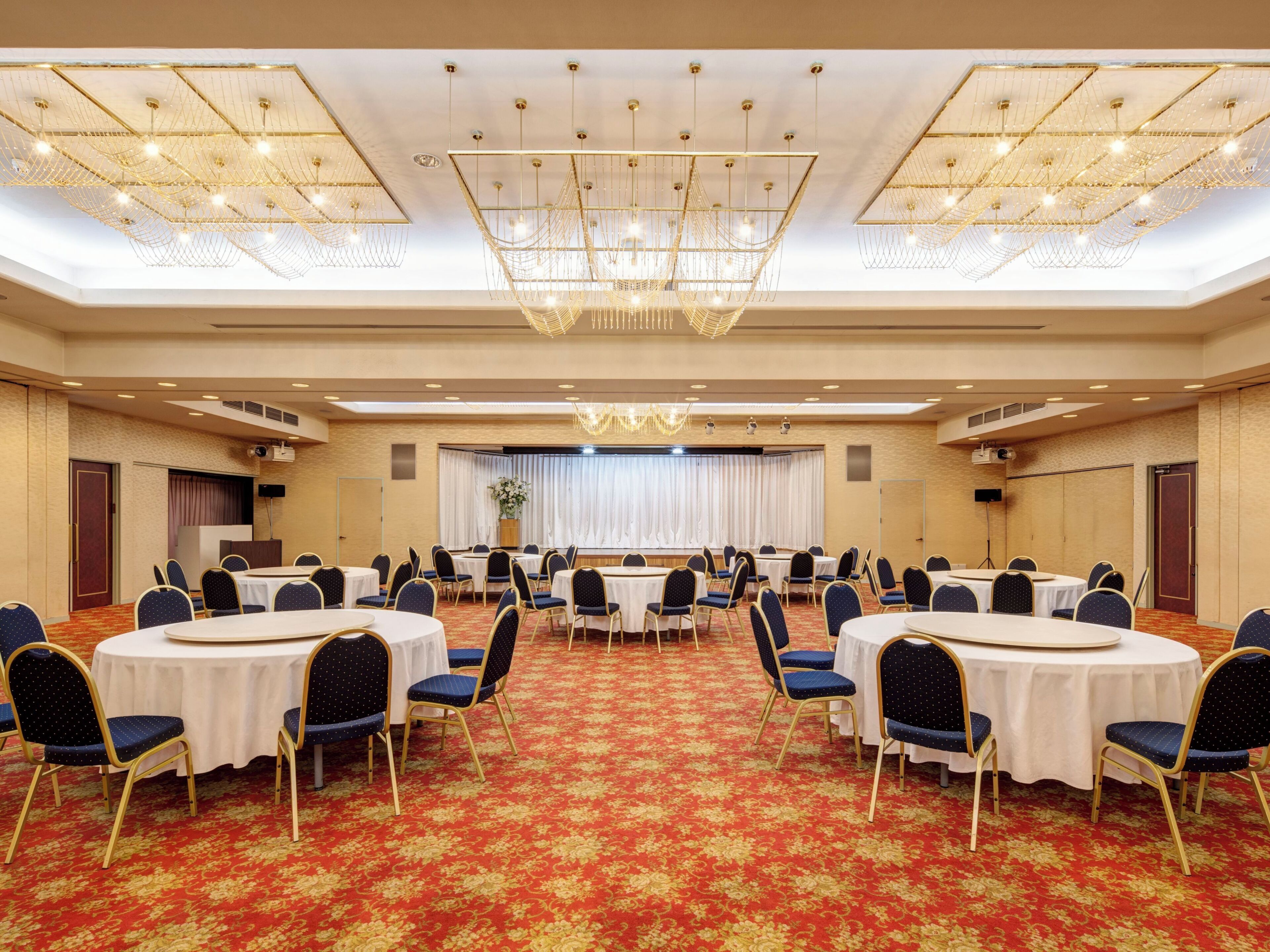 A conference room with round tables, blue chairs, and a red carpet.