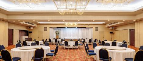 A conference room with round tables, blue chairs, and a red carpet.