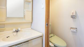Un baño con un lavabo blanco, un espejo, un inodoro y un dispensador de toallas de papel.
