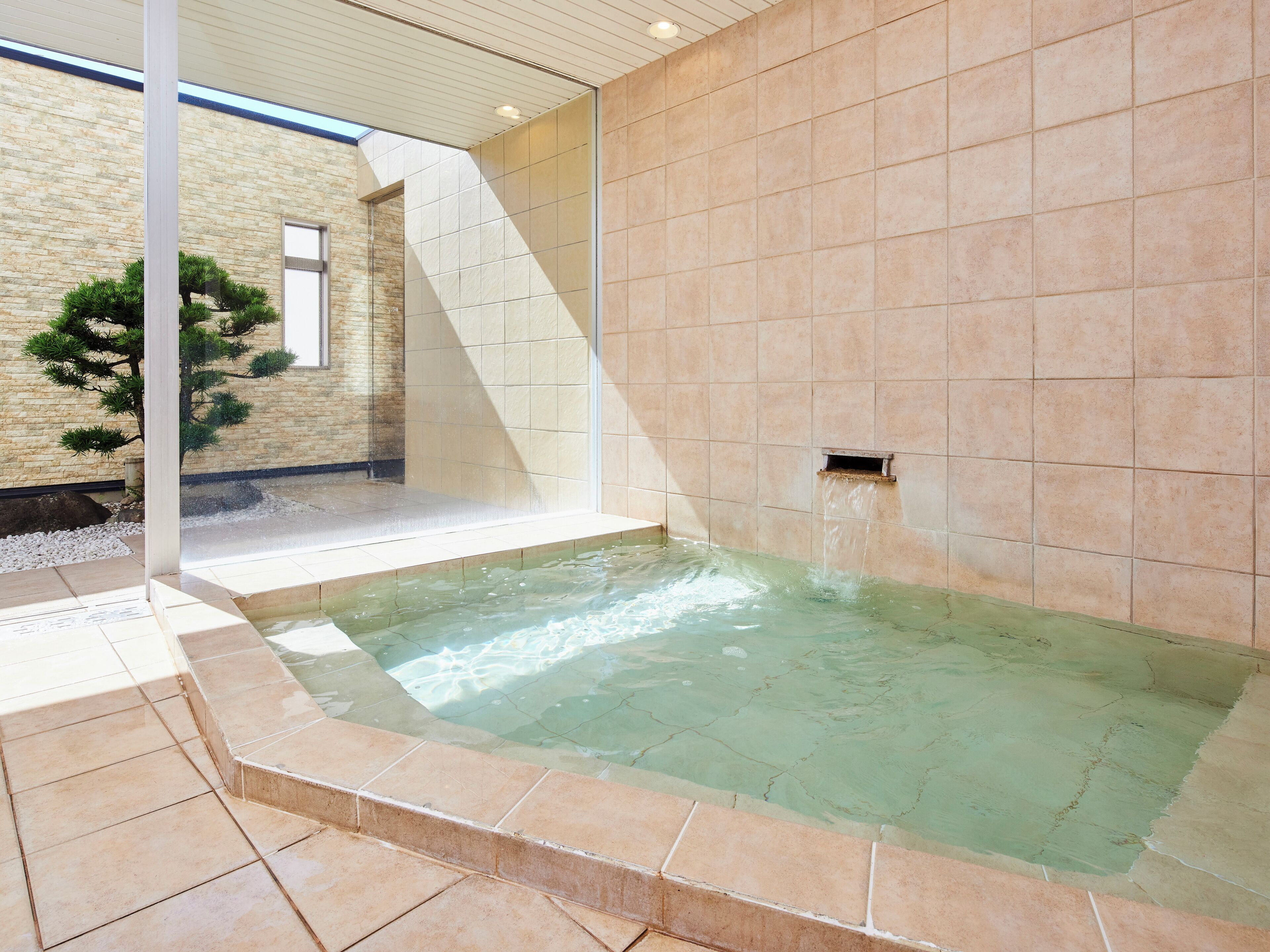 A spa area with a hot tub, tiled walls, and a stone wall in the background.