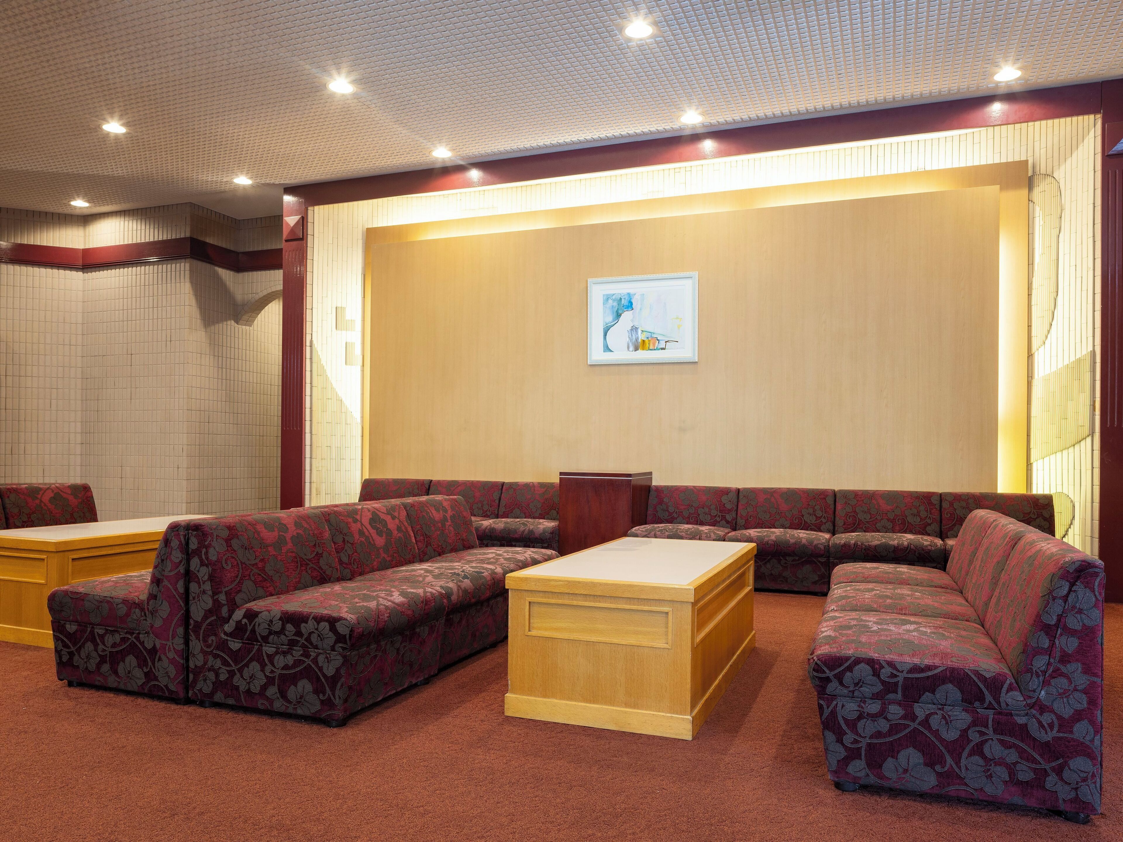 A lobby with a large seating area, a wooden reception desk, and a framed artwork on the wall.