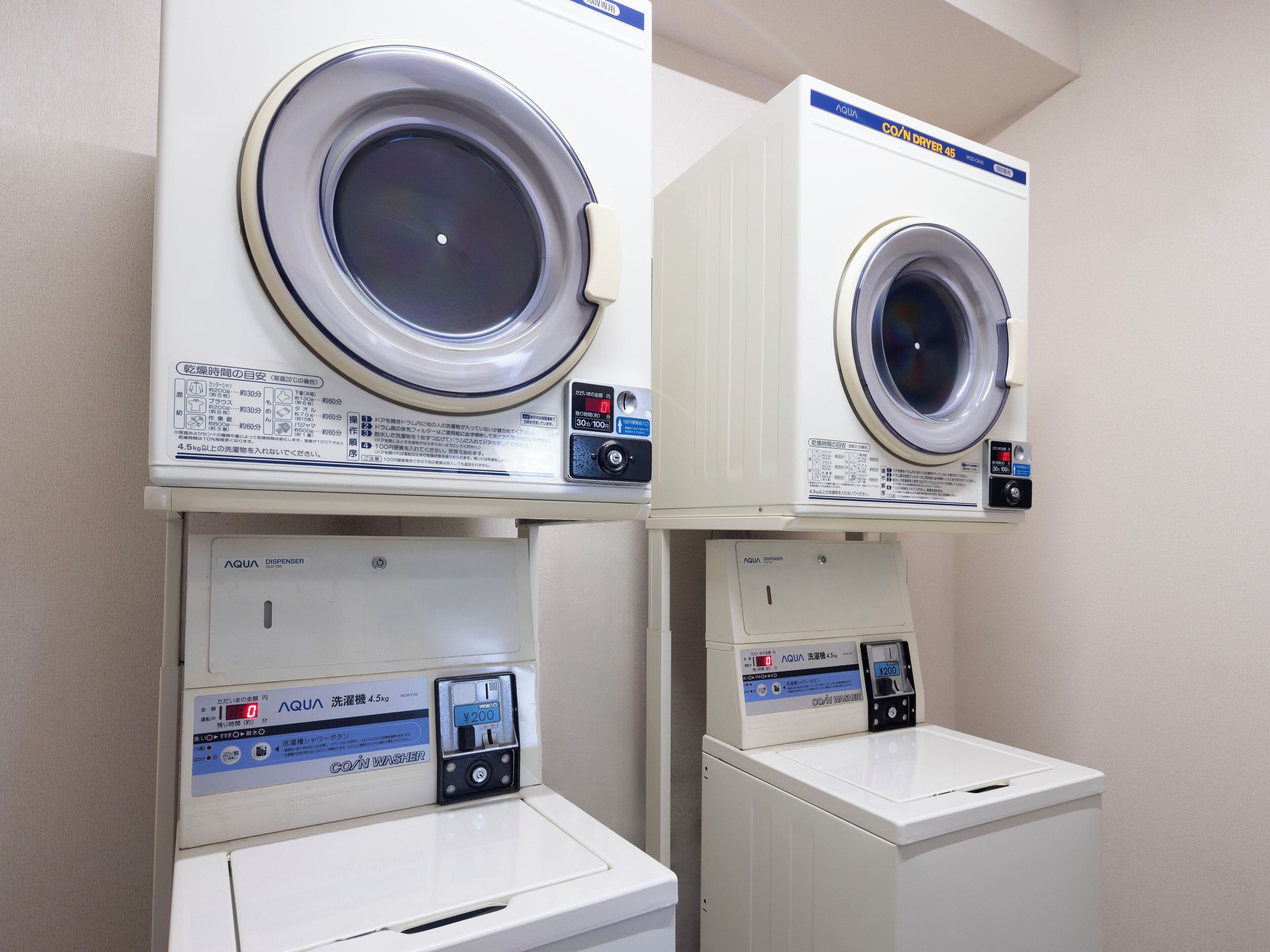 Two stacked laundry machines with control panels and a coin-operated dispenser.