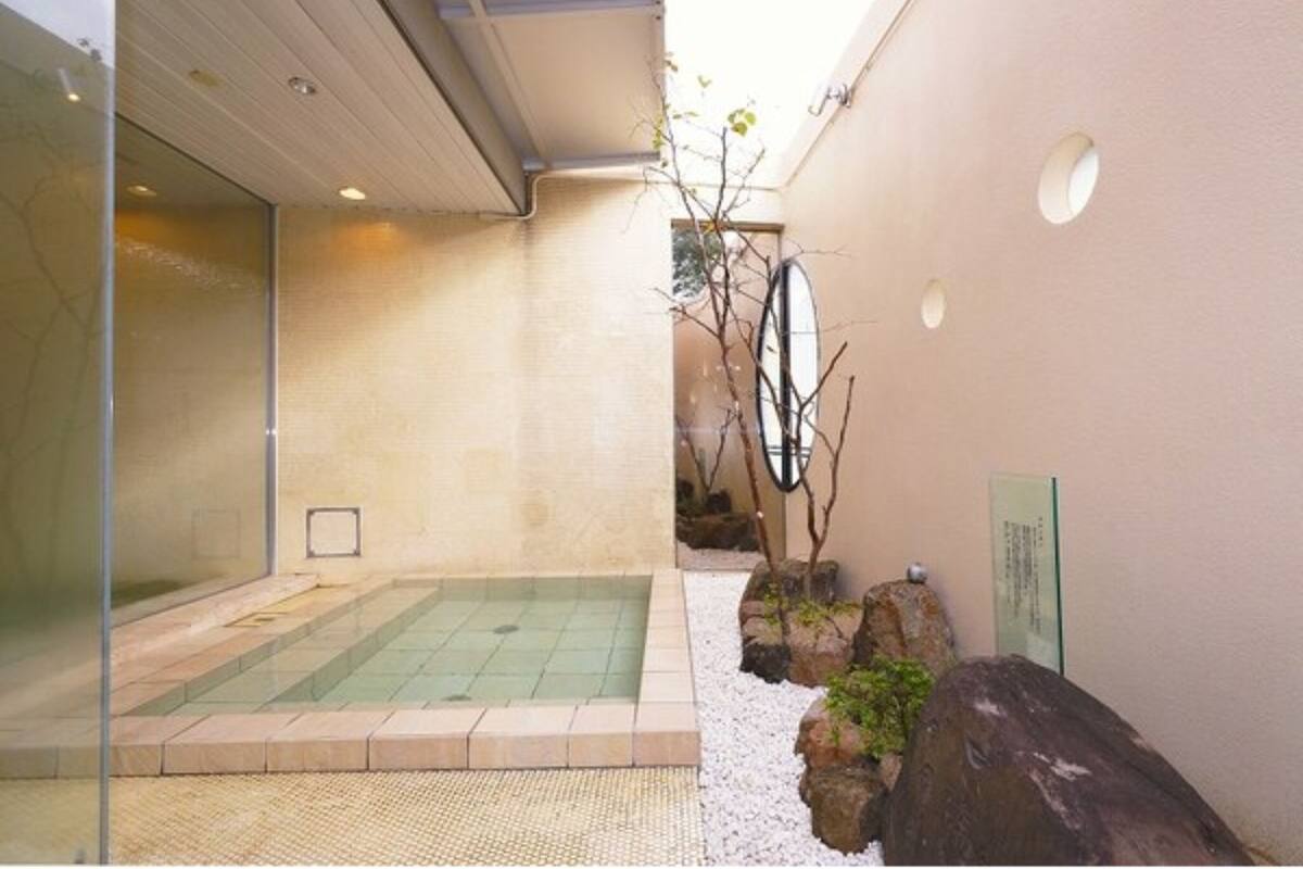 A modern spa area with a glass-enclosed hot tub, a small indoor pool, and a pebble-lined walkway.