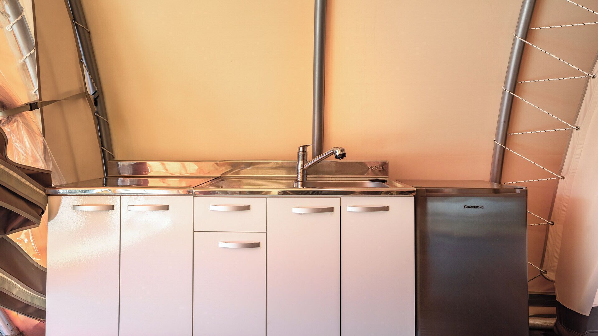 A compact kitchenette with a stainless steel sink, a dishwasher, and white cabinets.