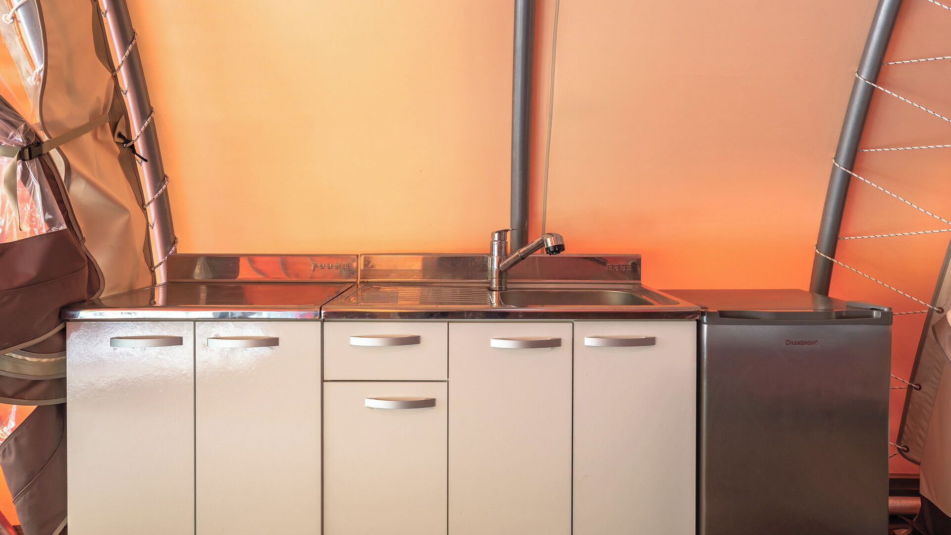 Una kitchenette con un lavamanos de acero inoxidable, estufa y refrigerador.