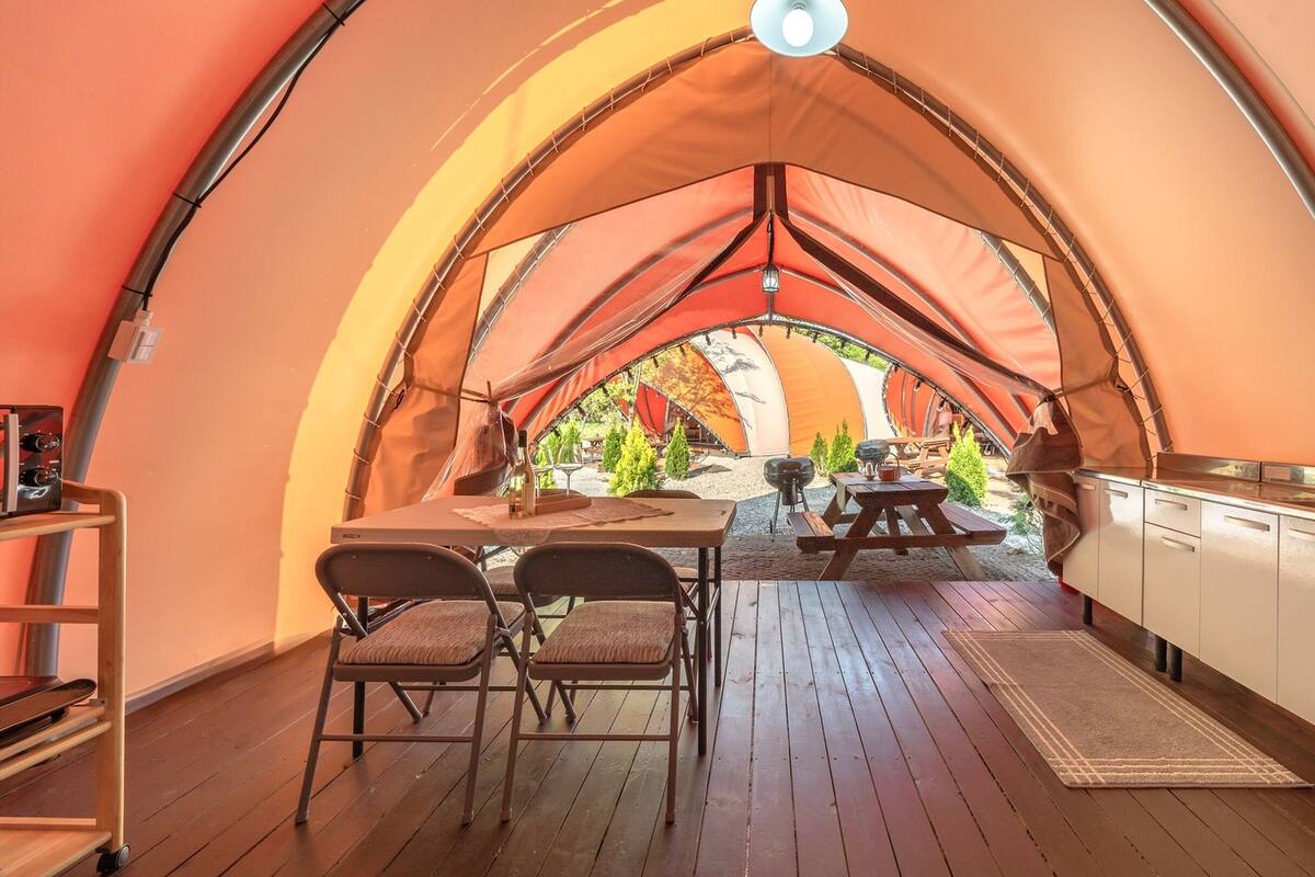 Una tienda acogedora y cerrada con terraza de madera, mesas de picnic y kitchenette.