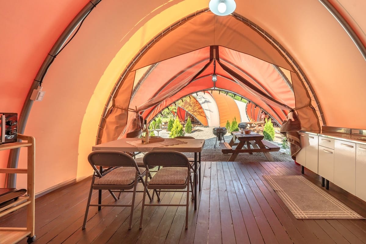 Une tente confortable et abritée, dotée d’une terrasse en bois, de tables de pique-nique et d’un coin cuisine.