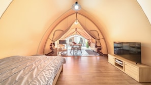 Een gezellige tentkamer met een bed, een televisie en een eethoek.