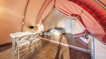 A cozy, compact room with a bed, a small table, and a chair.