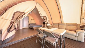 Un alojamiento en carpa acogedor con sofá, una mesa y sillas.