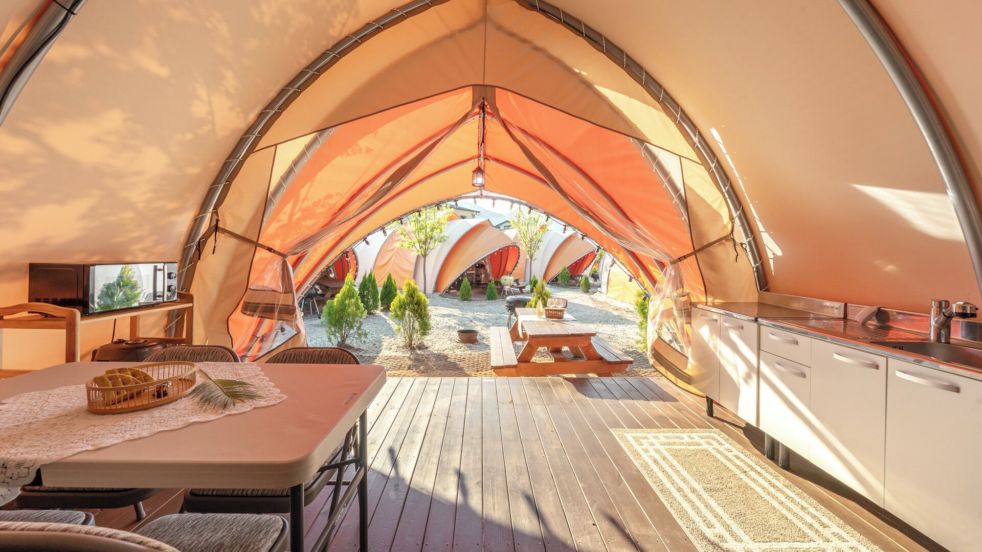 Un hébergement sous tente comprenant un espace repas, une cuisine et un coin salon extérieur.