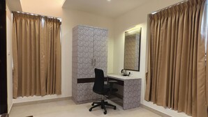 Quarto com escrivaninha, cadeira, guarda-roupa e espelho.