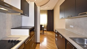 A modern kitchen with dark cabinets, a stove, and a dining area with a table and chairs.