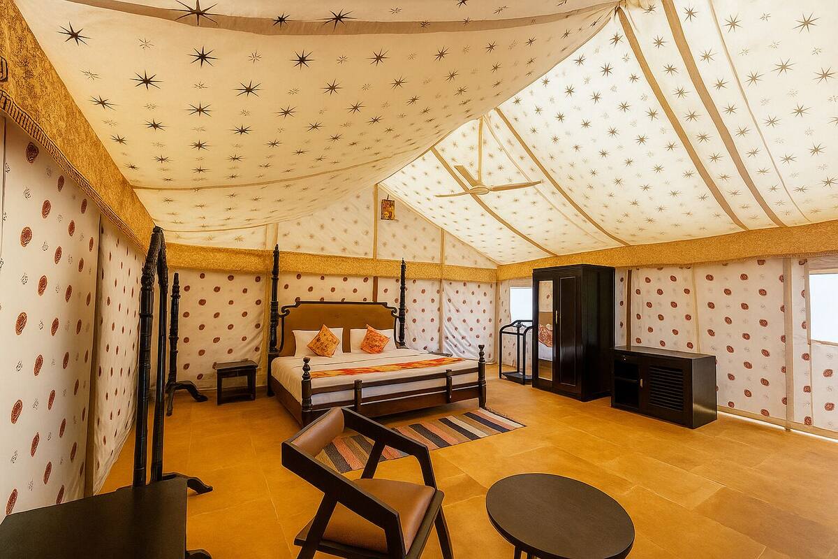 Ein zeltartiges Zimmer mit einem Himmelbett, einem kleinen Tisch, einem Sessel und einem Fernseher.