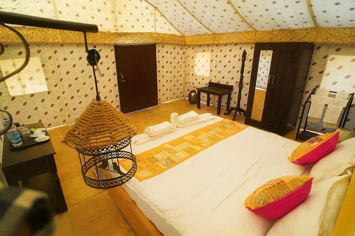 Ein Zimmer mit einem Bett, einer Hängelampe, einem kleinen Tisch und einer Tür.