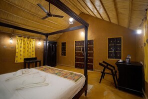 Ein Zimmer mit einem Himmelbett, einem Schreibtisch mit Stuhl und einem Kleiderschrank.