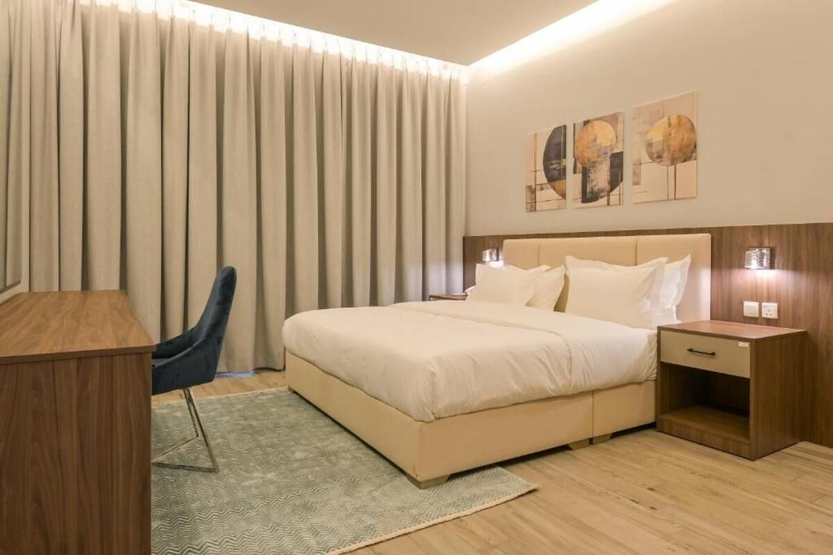 Une chambre d’hôtel avec un lit, un bureau, une chaise et une table de chevet.