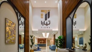 A modern hotel lobby with a central reception desk, seating areas, and a large mirror reflecting the space. - Tiara hotel (Jeddah)