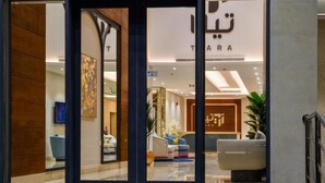 A modern hotel lobby with a reception desk, seating area, and a large window. - Tiara hotel (Jeddah)