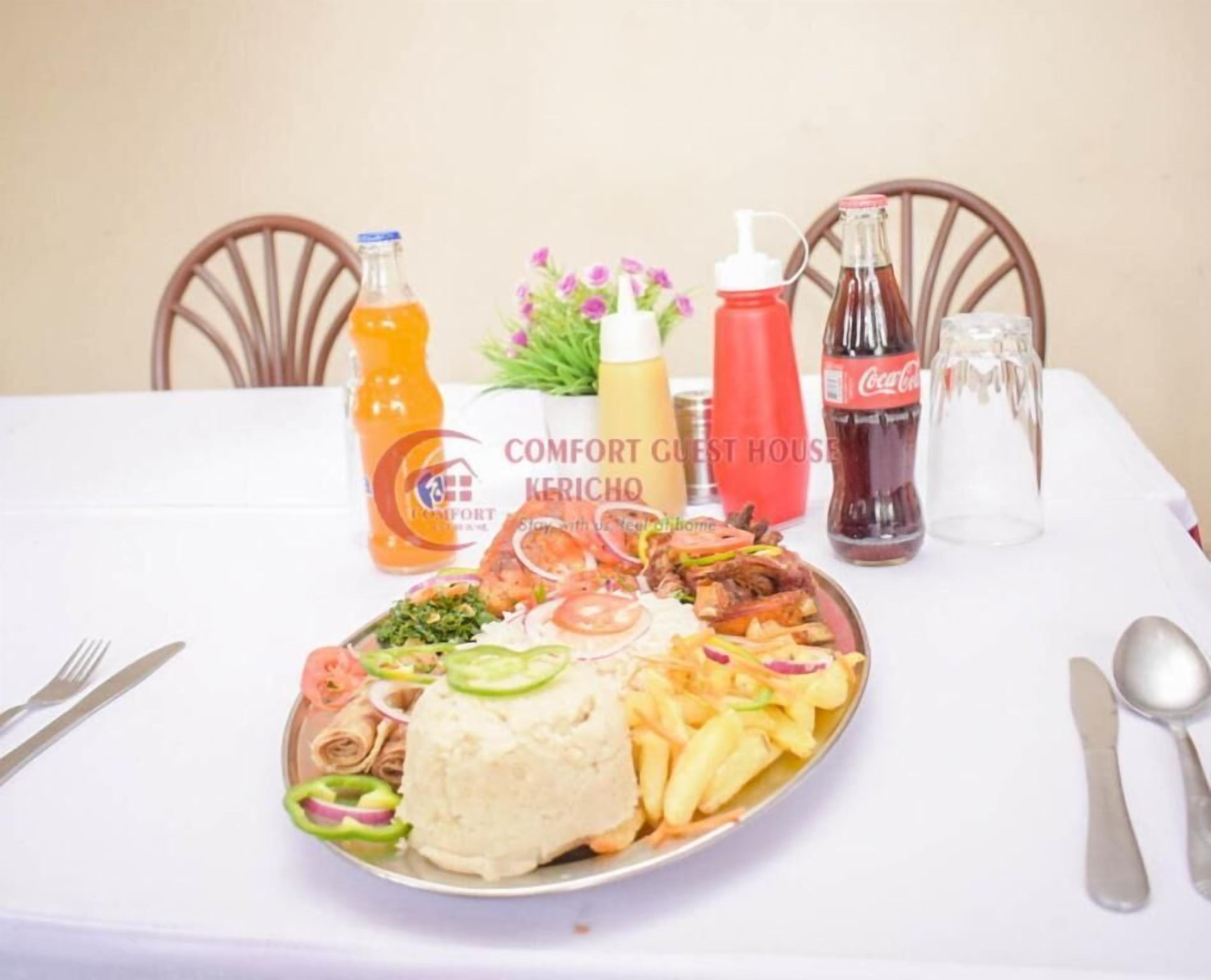 A dining table with a plate of food, condiments, and a bottle of Coca-Cola.