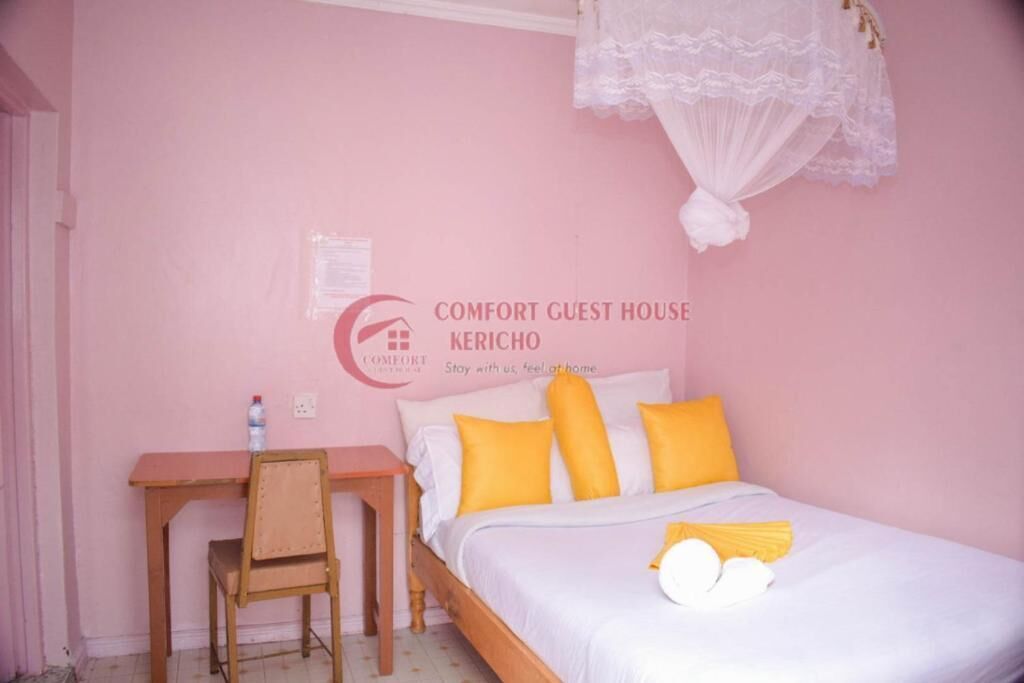 A pink-themed guest room with a bed, a desk, and a chair.
