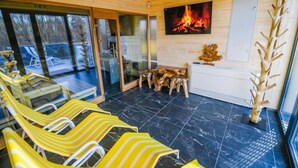 A wooden interior with a fireplace, yellow striped chairs, and a glass door leading outside. - Pensjonat Fitness i Spa Gregor (Zielona Góra)