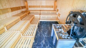 A sauna with wooden benches and a stone floor, featuring a large stone wheel and a water channel. - Pensjonat Fitness i Spa Gregor (Zielona G óra)