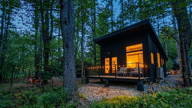 A cabin with a deck, surrounded by trees. - Nature view cabin in the pines w/ full bath - 05 (Freeport)