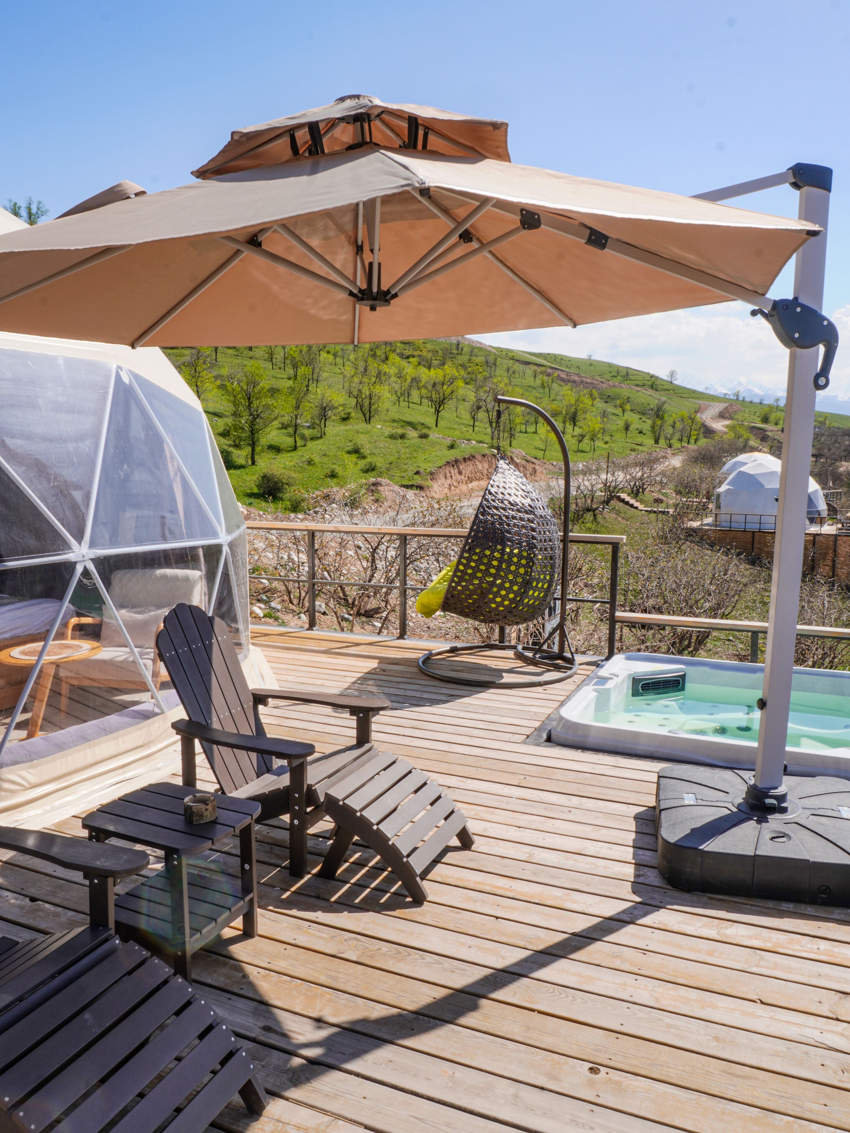 A wooden deck with outdoor seating, a hot tub, and a view of a green landscape with hills.